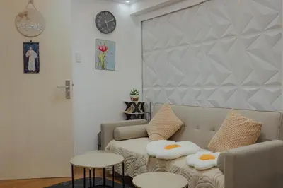 a living room with a couch and a clock on the wall at Family Friendly Stay UrbanDeca in Manila