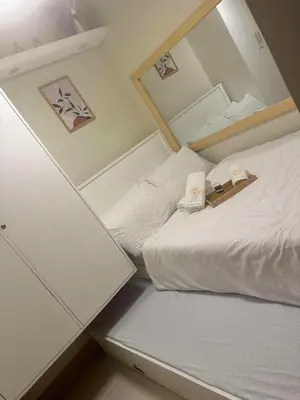 a small bedroom with a white bed with a mirror at Cassa Bella in Manila