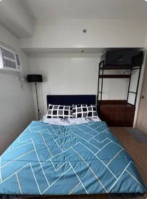 a bed in a bedroom with a blue comforter at Tulip Garden Apricot Southwoods Binan 1BR with Pool & gym in Biñan
