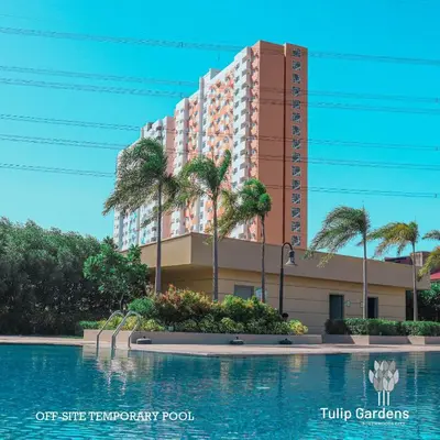 a building with palm trees in front of a swimming pool at Tulip Garden Apricot Southwoods Binan 1BR with Pool & gym in Biñan