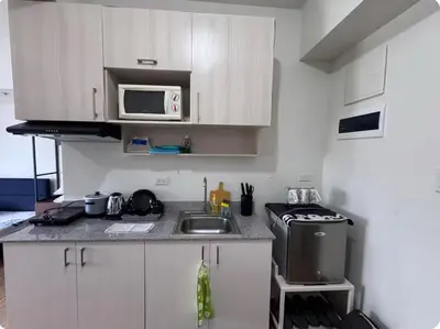 a small kitchen with a sink and a microwave at Tulip Garden Apricot Bldg 1BR with pool and Gym in Biñan