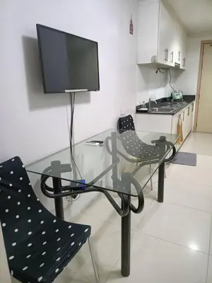 a glass table with two chairs and a flat screen tv at My Place in Manila