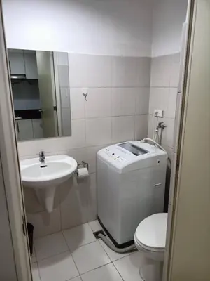 a white bathroom with a sink and a toilet and a mirror at My Place in Manila