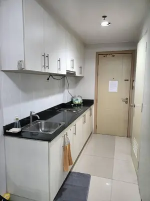a kitchen with white cabinets and a sink and a door at My Place in Manila