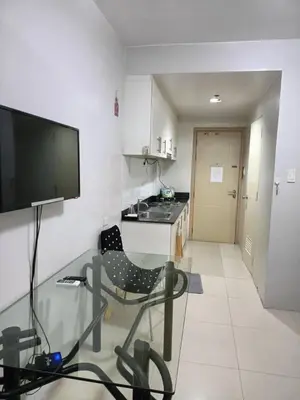 a living room with a glass table and a kitchen at My Place in Manila