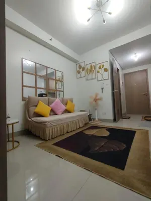 a living room with a couch with yellow and pink pillows at Sweet Staycation in Manila