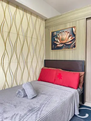 a bedroom with a bed with red pillows and a painting at LJ's escape 2BR COAST Residences in Manila
