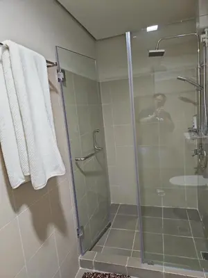 a shower in a bathroom with a man taking a picture at Condo next door in Manila