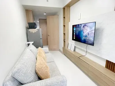 a living room with a couch and a tv on a wall at 212 Budget Condo at Shore 3 The Dwelling place in Manila
