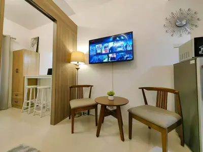 a living room with a table and chairs and a tv at 1-bedroom with balcony in Manila