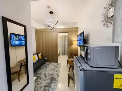 a living room with a microwave on top of a refrigerator at 1-bedroom with balcony in Manila