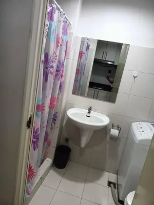 a bathroom with a sink and a shower curtain at Roiden Sea Residences in Manila
