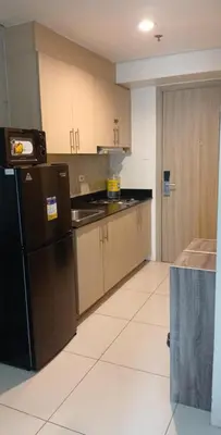 a kitchen with a black refrigerator and wooden cabinets at Staycation at a Breeze 01 in Manila