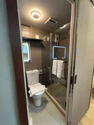 a small bathroom with a toilet and a shower at The Crystal Cove Cabin in Puting Kahoy