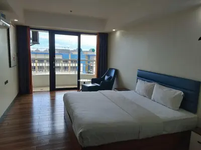 a bedroom with a bed and a chair and a window at Hotel S in Manila