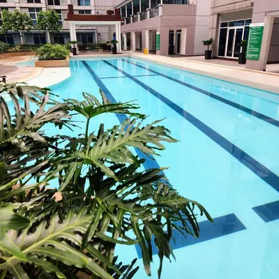 a large swimming pool with a plant in the foreground at StudioUnit Near Airport up to 3pax WiFi in Manila