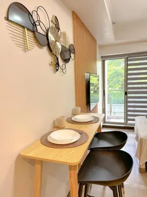 a dining room with a wooden table and two black chairs at Studio Suite at Fairway Terraces near NAIA T3 in Manila