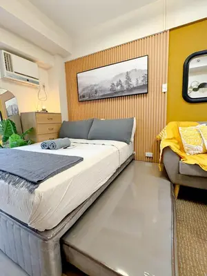 a bedroom with a large bed and a chair at Studio Suite at Fairway Terraces near NAIA T3 in Manila