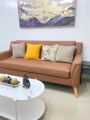 a living room with a brown couch and a white table at Spacious 2BR Suites at MOA in Manila