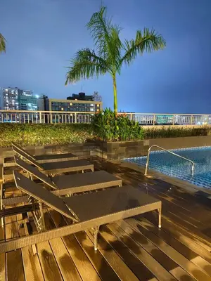 a deck with chairs and a swimming pool with palm trees at Comfortable Cozy Staycation in Manila
