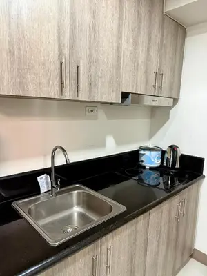 a kitchen with a stainless steel sink and wooden cabinets at Comfortable Cozy Staycation in Manila