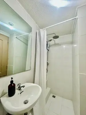 a white bathroom with a sink and a shower at 2BR Relaxing Oasis with pool access Sorrento Oasis in Manila