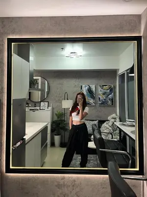 a woman standing in front of a mirror in a kitchen at R&D comfy staycation in Manila