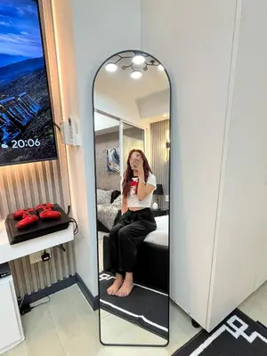 a woman sitting on a bed in front of a mirror at R&D comfy staycation in Manila