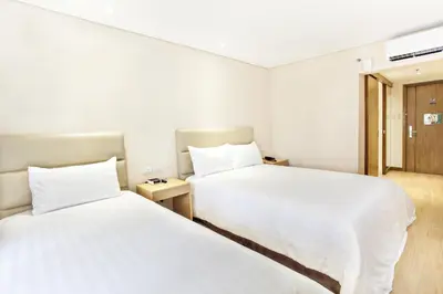 two beds in a hotel room with white sheets at Jinjiang Inn - Ortigas in Manila