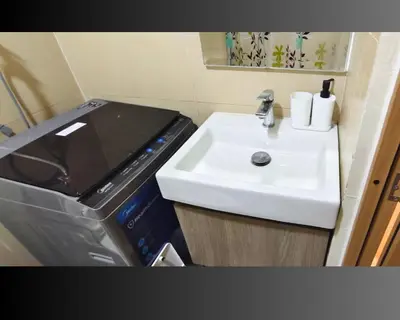 a bathroom with a sink and a washing machine at Las Vegas of the Philippines in Pasay Manila Luxury Near NAIA Airport x Solaire x Okada x City of Dreams and Casinos Enjoy FREE Pool Access n HighSpeed WIFI and Netflix Comfort with ResortType Living Secure Your Limited Offer This Month in Manila