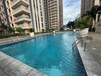 a large swimming pool in a city with tall buildings at Spacious Staycation with venice grand canal view in Manila