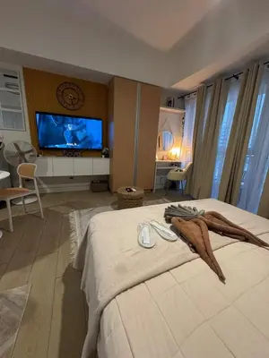 a bedroom with a large bed with a tv on the wall at Spacious Staycation with venice grand canal view in Manila
