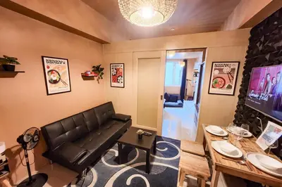 a living room with a black leather couch and a table at Cozy Pool & City View 1br Apt in Makat with Netflix in Manila