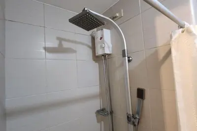 a shower with a shower head in a bathroom at Cozy Pool & City View 1br Apt in Makat with Netflix in Manila