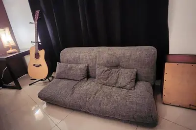 a couch and a guitar in a living room at Cozy Pool & City View 1br Apt in Makat with Netflix in Manila