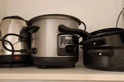 a slow cooker and a toaster on a shelf at Cozy Pool & City View 1br Apt in Makat with Netflix in Manila
