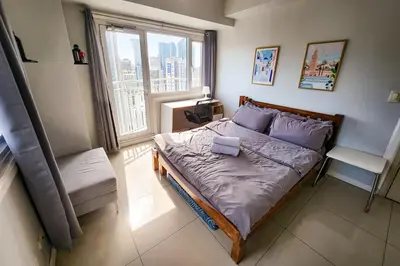 a small bedroom with a bed with a window at Amazing City View 2br apartment in Makati - 70sqm in Manila