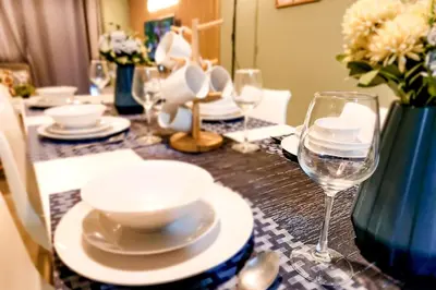a table with plates and a glass of wine at Amazing City View 2br apartment in Makati - 70sqm in Manila