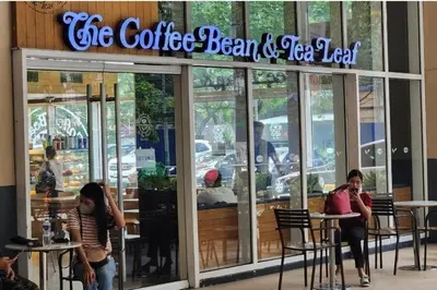 a coffee bean and tea leaf restaurant with people sitting outside at Luxury 2br in Makati with Billiard & Netflix in Manila