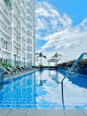 a swimming pool at a resort with chairs and a building at Jessa Rios Coast Staycation in Manila