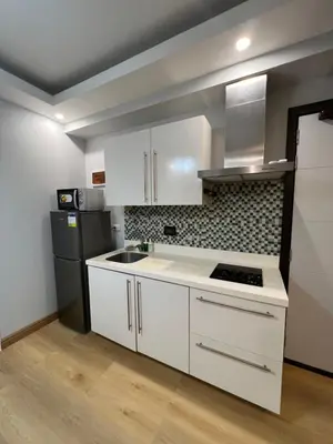 a kitchen with white cabinets and a black refrigerator at Acqua Escape in Manila