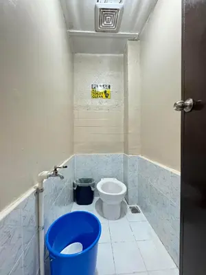 a bathroom with a toilet and a blue bucket at 88Ap Lodging House San Marcelino in Manila