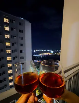 a person holding two glasses of wine on a balcony at Divine Staycation in Manila