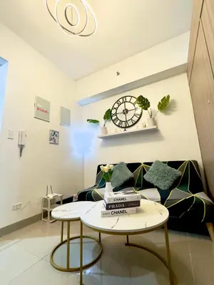 a living room with a couch and a clock on the wall at Divine Staycation in Manila
