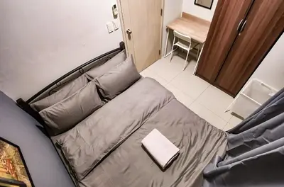 a bed in a small room with a desk and a table at Gaming 2br in Makati with City View Arcade Netflix in Manila