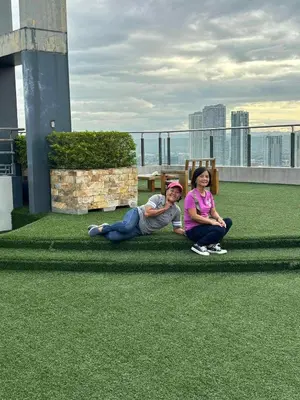 two people sitting on the grass on a roof at 52sqmComfy2BR and 2BA Resort-inspired Flair Towers Condo in Manila
