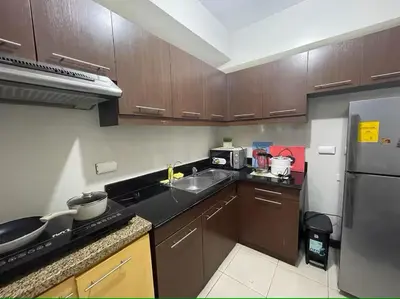 a kitchen with wooden cabinets and a stainless steel refrigerator at 52sqmComfy2BR and 2BA Resort-inspired Flair Towers Condo in Manila