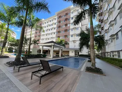 a hotel with a swimming pool and palm trees at Aras Solace Place in Trece Martires