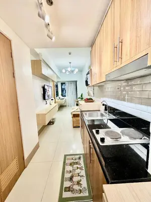 a kitchen with wooden cabinets and a black counter top at Minimalist Chic Condo near MOA-Shore3 Tower2 in Manila