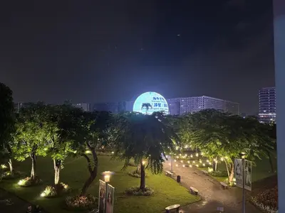 a park with trees and a lighted building at night at Minimalist Chic Condo near MOA-Shore3 Tower2 in Manila